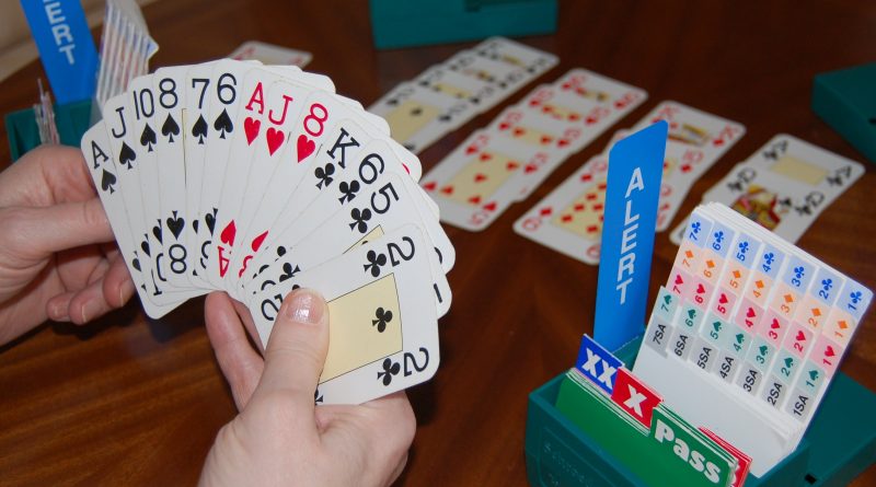 Hand holding cards at a table with cards played and boxes