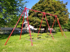 Image of the old ,red four swing set being replaced