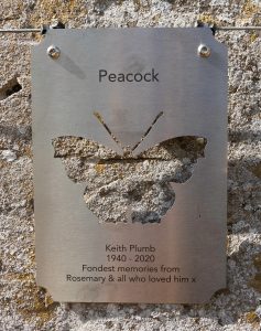 Steel plaque on stone wall, with butterfly shape cut out and text dedication