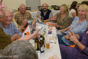 Group of villagers at a table enjoying drinks and a chat